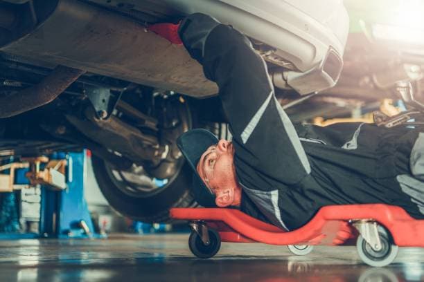 Auto mechanic performing engine repairs in a garage